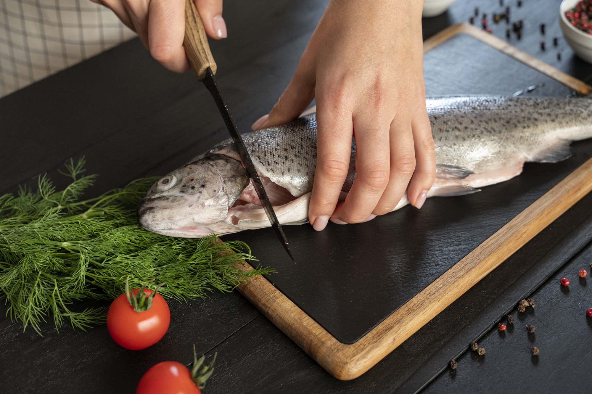 Dettaglio mani che sfilettano un pesce